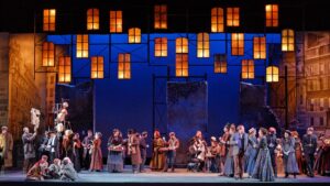 A crowd gathers under warm lights on stage for Opera Colorado's 2017 production of La bohème.